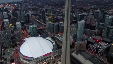 Vista-Aérea-Frente-A-La-Torre-Cn-Y-El-Centro-De-Rogers-En-El-Centro-De-Toronto,-Noche-Sombría-En-Ontario,-Canadá---Inclinación,-Disparo-De-Drones