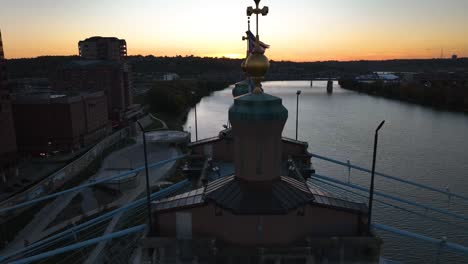 Vista-Aérea-Sobre-La-Bandera-En-El-Puente-Roebling,-Puesta-De-Sol-En-Covington,-Kentucky,-Ee.uu.---Reversa,-Disparo-De-Drones