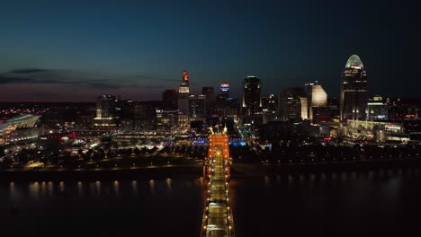 Luftbild-über-Die-Roebling-Bridge-Mit-Skyline-Von-Cincinnati-Im-Hintergrund,-Nacht-In-Ohio,-USA---Rückzug,-Drohnenaufnahme