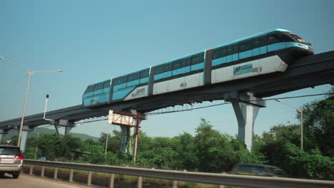 Breite-Aufnahme-Der-Mmrda-Mumbai-Monorail,-Die-In-Den-Nachmittagsstunden-Neben-Dem-Eastern-Express-Highway-Fährt,-Wie-Aus-Dem-Fenster-Eines-Autos-Gesehen