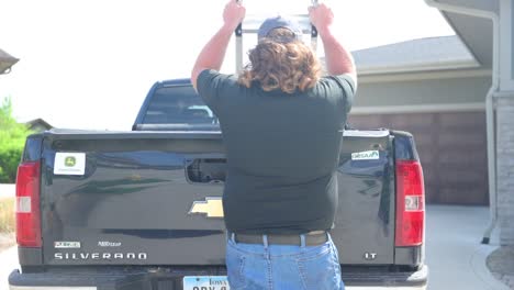 construction-worker-grabs-a-ladder-out-of-the-back-of-a-pick-up-truck-for-a-job