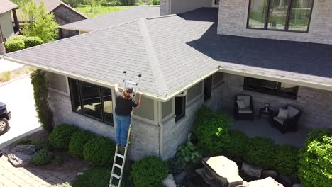 Drone-shot-of-a-Gutter-inspection-from-a-ladder-by-a-handy-man-carpenter