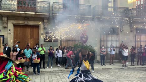 slow-motion-shot-of-an-indigenous-woman-with-traditional-oaxaca-costumes-and-fireworks-on-her-head-during-a-wedding-celebration-in-the-city-of-oaxaca-mexico,-dancing-along-with-the-guests