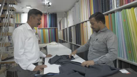 Un-Hombre-Indio-De-Mediana-Edad-Está-Comprando-Tela-De-Ropa-Cruda-Para-Coser-Ropa-Formal-En-Una-Sastrería-Local