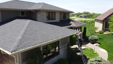 Drone-shot-of-a-Gutter-inspection-from-a-ladder-by-a-handy-man-carpenter