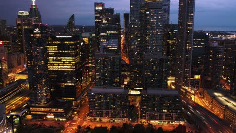 Hyperlapse-of-buildings-in-South-Core,-traffic-and-the-railway-station-in-Toronto,-Canada---pull-back-aerial