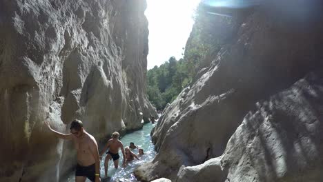 Gente-Explorando-El-Paso-Del-Cañón-De-La-Corriente-De-Agua-Desde-El-Agua-De-Manantial-Natural-De-Montaña-En-Fonts-De-L&#39;algar,-Alicante,-España