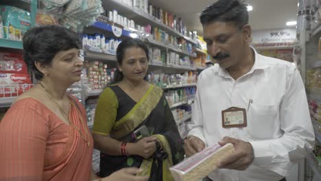 A-consumer-affairs-supervisor-points-out-to-two-middle-aged-Indian-women-when-shopping-for-retail-items-that-have-misleading-packaging-practices