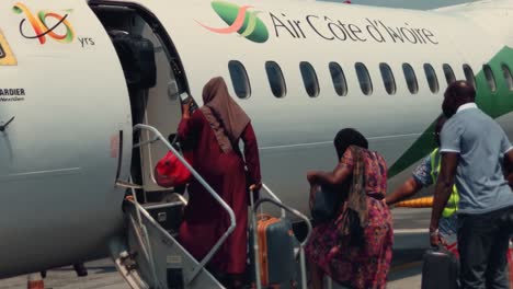 Pasajeros-Africanos-Que-Abordan-Un-Avión-Bombardier-Dhc-8-Q400-De-Air-Cote-D&#39;Ivoire-En-El-Aeropuerto-Internacional-Félix-Houphouët-Boigny-De-Abidjan