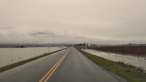 Driving-on-almost-flooded-countryside-road,-POV-view