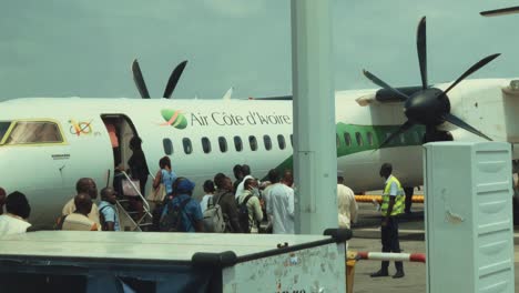 Afrikanische-Passagiere-Steigen-Aus-Dem-Flughafenbus-Aus,-Um-Am-Internationalen-Flughafen-Abidjan-Félix-Houphouët-boigny-In-Ein-Air-Cote-D&#39;ivoire-Bombardier-Dhc-8-Q400-Flugzeug-Einzusteigen