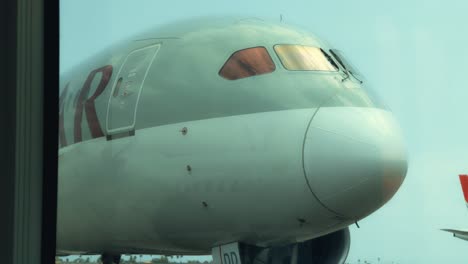 Qatar-Airways-Boeing-787-Dreamliner-En-La-Puerta,-Vista-De-La-Nariz-Desde-El-Interior-De-Un-Autobús,-En-El-Aeropuerto-Internacional-De-Abidjan-Félix-Houphouët-Boigny