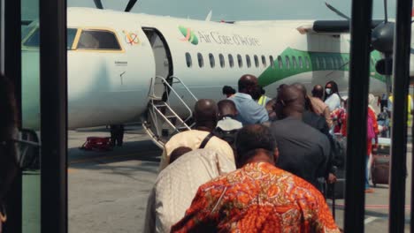 Pasajeros-Africanos-Haciendo-Cola-Para-Abordar-Un-Avión-Bombardier-Dhc-8-Q400-De-Air-Cote-D&#39;Ivoire-En-El-Aeropuerto-Internacional-Félix-Houphouët-Boigny-De-Abidjan