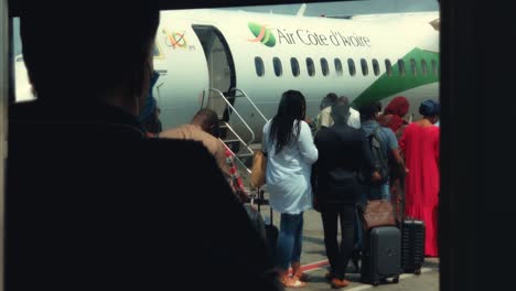 Pasajeros-Haciendo-Cola-Para-Abordar-Un-Avión-Bombardier-Dhc-8-Q400-De-Air-Cote-D&#39;Ivoire-En-El-Aeropuerto-Internacional-Félix-Houphouët-Boigny-De-Abidjan