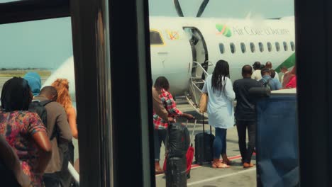 Afrikanische-Passagiere,-Die-Ein-Air-Cote-D&#39;ivoire-Bombardier-Dhc-8-Q400-Flugzeug-Am-Internationalen-Flughafen-Abidjan-Félix-Houphouët-boigny-Besteigen,-Blick-Aus-Den-Fenstern-Des-Flughafenbusses