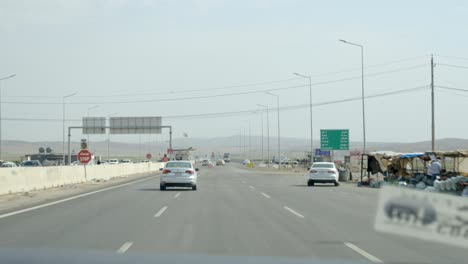 Driving-up-to-a-checkpoint-on-a-highway-in-Iraq-with-a-sign-for-Erbil,-Kirkuk-and-Suleimani