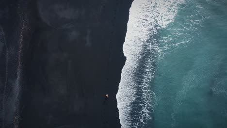 Impresionante-Sobre-La-Foto-De-Un-Hombre-Corriendo-En-Una-Playa-De-Arena-Negra-Cerca-De-Las-Olas,-Islandia