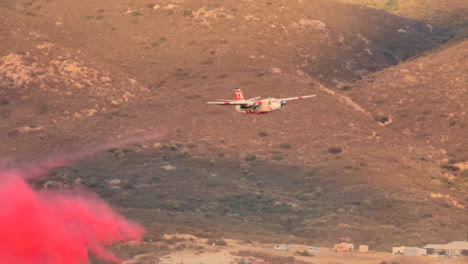 Ein-Löschflugzeug-Lässt-Rosafarbenes-Chemisches-Wasser-Auf-Schroffes-Hügelgelände-Fallen,-Um-Ein-Lauffeuer-In-Kalifornien-Zu-Löschen