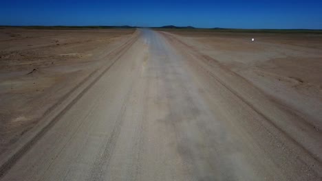 Drone-shot-of-the-Namib-Naukluft-National-Park-in-Namibia---drone-is-flying-towards-a-car-in-steppe-surrounding