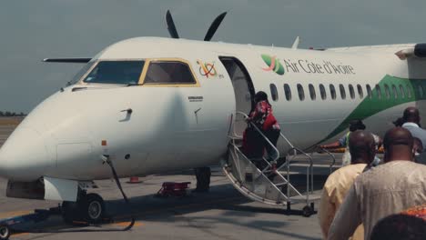 Pasajeros-Africanos-Que-Abordan-Un-Avión-Bombardier-Dhc-8-Q400-En-El-Aeropuerto-Internacional-Félix-Houphouët-Boigny-De-Abidjan-En-Un-Día-Soleado