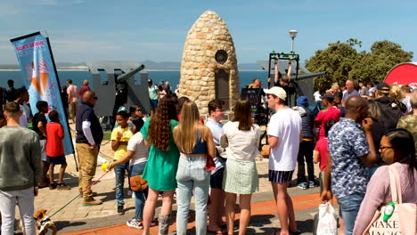 Visitors-around-War-Memorial-with-naval-guns-during-Whale-Festival,-Hermanus