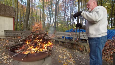 Hombre-Con-Guantes-En-Clima-Frío-Poniendo-Maderas-En-El-Fuego-Del-Campamento