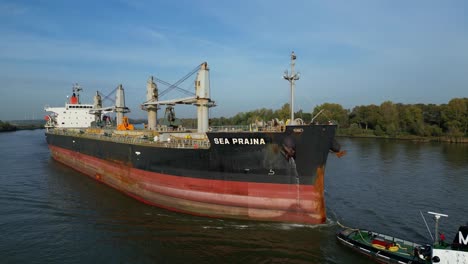 Aerial-View-Of-Tug-Boat-Assisting-Sea-Prajna-Bulk-Carrier-Along-Oude-Maas-In-Puttershoek