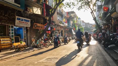 Pov-Caminando-Por-La-Carretera-Con-Motos-Pasando-En-Hanoi-Contra-La-Luz-Del-Sol-Bengalas-A-Través-De-Los-árboles