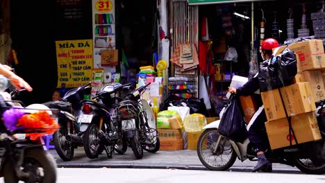 Mensajeros-De-Motos-Que-Transportan-Cajas-Recorriendo-El-Ajetreado-Distrito-De-Negocios-De-Hanoi