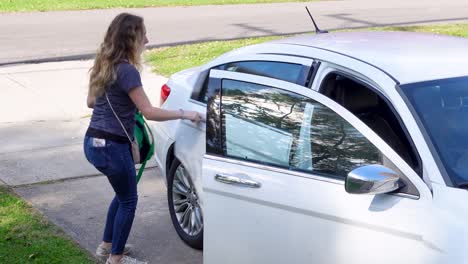 Schöne-Dame,-Die-Ihre-Sachen-In-Ein-Weißes-Auto-Legt-Und-Sich-Darauf-Vorbereitet,-Von-Zu-Hause-Aus-Zu-Starten