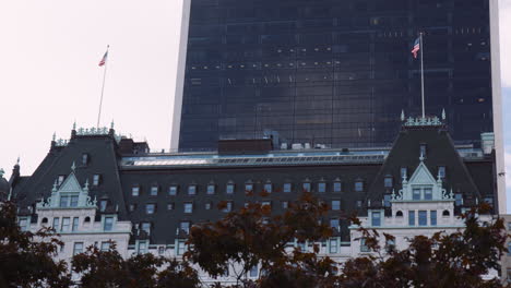 Top-Roof-and-Upper-Floors-of-Plaza-Hotel-Building-Facade-in-New-York-City-Manhattan-Usa,-American-Flag-on-Top-of-Building,-Urban-Architecture-and-Cityscape,-Modern-Tower-Behind-the-Hotel