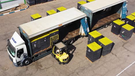 forklift-Put-cargo-pallets-into-Semi-Trailer-Truck,-orbit-aerial-shot,-freight-Transport-By-DAF-trucks