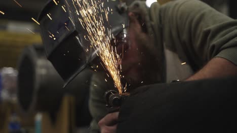 Close-up,-blue-collar-worker-grinding-metal-with-face-shield-off-in-workshop