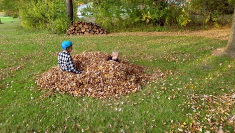 Dos-Niños-Saltando-Alegremente-En-Un-Montón-De-Hojas-Caídas-En-La-Temporada-De-Otoño