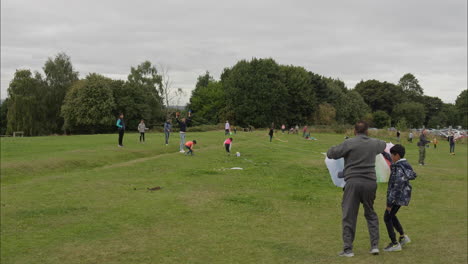 Familia-Asiática-Muestra-A-Los-Niños-Cómo-Volar-Cometas-En-Un-Festival-De-Cometas-En-Heath-Common-Wakefield-Un-Aburrido-Día-De-Primavera