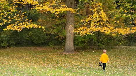 Lindo-Niño-Rubio-Corriendo-Sobre-Hojas-De-Otoño-Caídas-Jugando-Con-Su-Juguete-En-La-Naturaleza