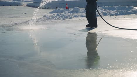 Arbeiter,-Der-Wasser-Sprüht,-Um-Die-Oberfläche-Der-Eisbahn-Im-Freien-Zu-Glätten,-Zeitlupe