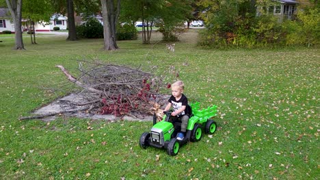 Niño-Pequeño-Y-Lindo-Conduciendo-Un-Tractor-Felizmente-Verde-Sobre-El-Césped-En-El-Patio-De-La-Casa