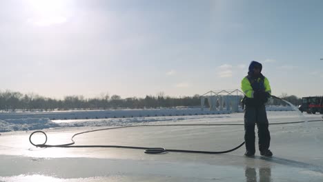 Trabajador-De-Mantenimiento-Rociando-Agua-En-La-Pista-De-Hielo-Del-Lago-Al-Aire-Libre