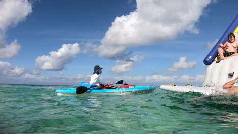 Lifeguard-at-sea-on-the-watch-|-Life-guard-on-duty-watching-kids-playing-on-beach-on-huge-balloon-floating-on-water-|-rescue,-security,-Kayak,-beach,-kids,-vacation,-tourism,-travel,-Caribbeans