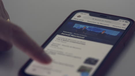 El-Dedo-De-La-Mujer-Desplazándose-A-Través-De-Su-Aplicación-De-Teléfono-Inteligente-Twitter---Primer-Plano-Aislado