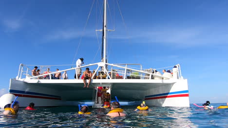 Menschen,-Die-Es-Genießen,-Im-Ozean-Zu-Schwimmen-Und-Auf-Ein-Katamaran-Segelboot-Umzuziehen-|-Touristen,-Die-Nach-Dem-Schnorchelabenteuer-Ins-Boot-Ziehen-|-Katamaran-bootsfahrt-Mitten-Im-Karibischen-Meer