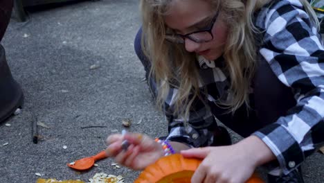 Süßes-Blondes-Mädchen,-Das-Mit-Schwarzem-Stift-Auf-Orange-Kürbis,-Halloween-Malt