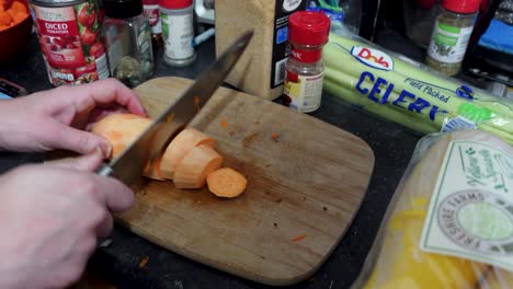 Persona-Cortando-Con-Un-Cuchillo-Grande-Las-Verduras-En-Rodajas-En-Una-Tabla-De-Madera,-De-Cerca