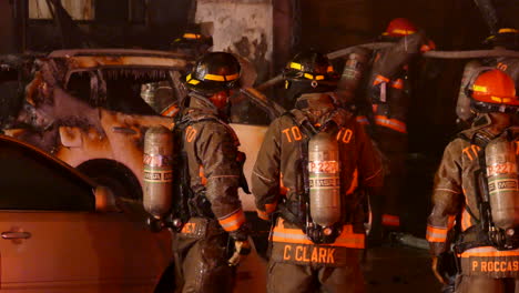 Car-burnt-out-after-catching-fire,-firemen-standing-on-scene-while-other-still-fighting-fire