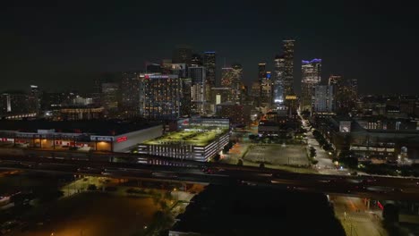 Luftaufnahme-über-Den-Verkehr-Auf-Der-Interstate-69-In-Richtung-Der-Wolkenkratzer-Von-Houston-City,-Nacht-In-Texas,-Usa---Aufsteigend,-Drohne-Erschossen