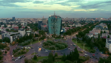 Plaza-Charles-De-Gaulle-Al-Atardecer-Con-Tráfico-Y-Vista-Aérea-Del-Edificio-De-Oficinas,-Bucarest,-Rumania