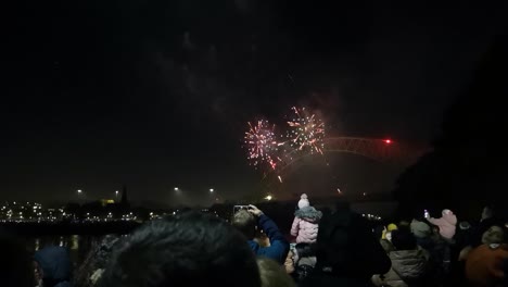 Multitud-Mira-Colorido-Festival-De-Fuegos-Artificiales-Explotando-En-El-Puente-Del-Jubileo-De-Plata,-Ancho