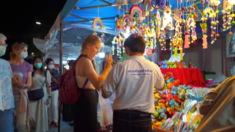 Joven-Viajera-Regateando-Con-Un-Anciano-Asiático-En-El-Mercado-Nocturno