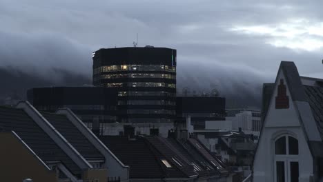 Lapso-De-Tiempo-De-La-Sede-De-La-Ciudad-De-Medios-De-Bergen---Lapso-De-Tiempo-De-La-Mañana-Desde-La-Oscuridad-Hasta-El-Anochecer-Con-Luz-En-Las-Ventanas-Y-Niebla-Y-Nubes-En-El-Fondo---Noruega